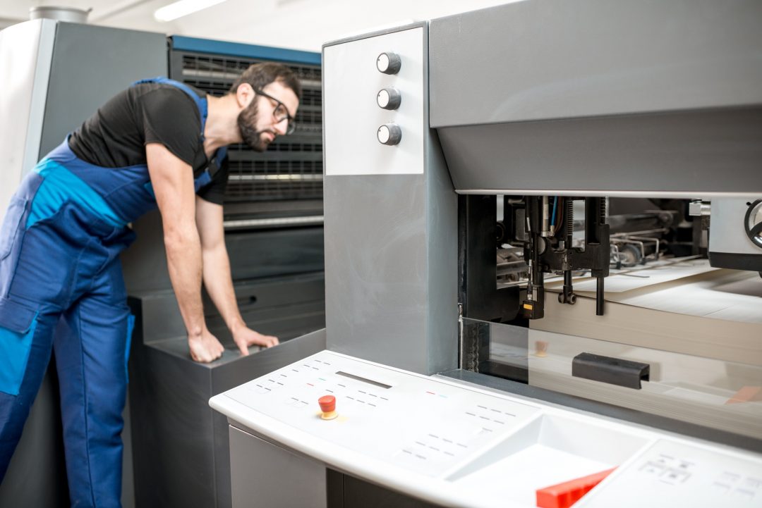 Technikexperte prüft Druckmaschinensteuerung in einer Druckerei.